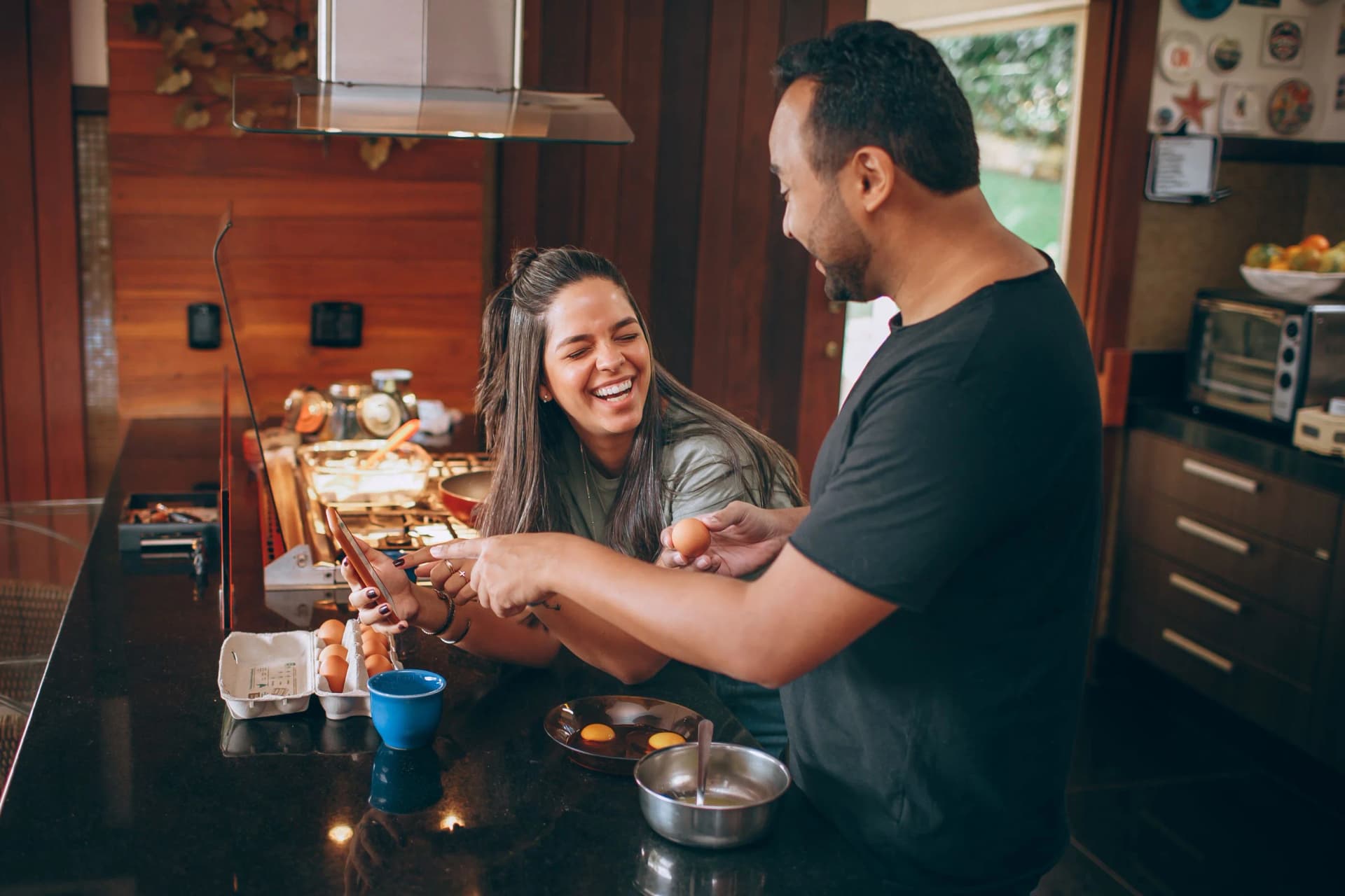 Zwei Menschen kochen zusammen, eine hält dabei das Telefon in der Hand